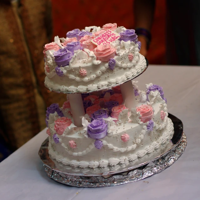 a triple tiered wedding cake that was topped with pink and lavender flowers