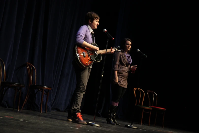 two people that are standing up with a guitar