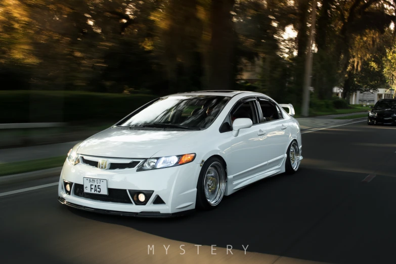 a white civic car on the road with trees in the background