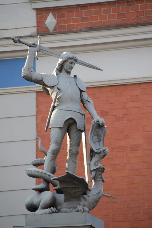 statue of a man holding a sword and spear standing in front of a building