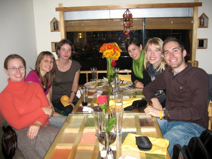 five young adults are sitting around the table and enjoying dinner