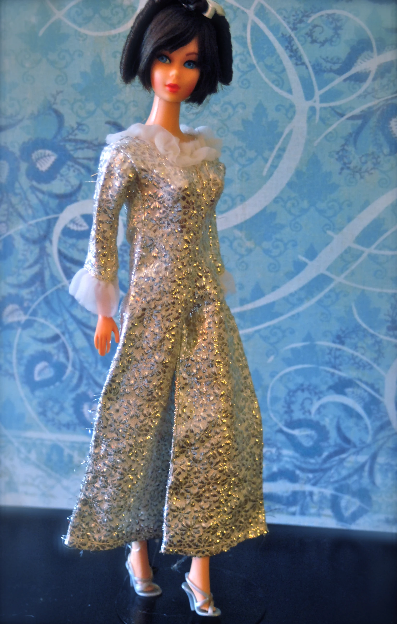 a doll is wearing a gold dress and white shoes