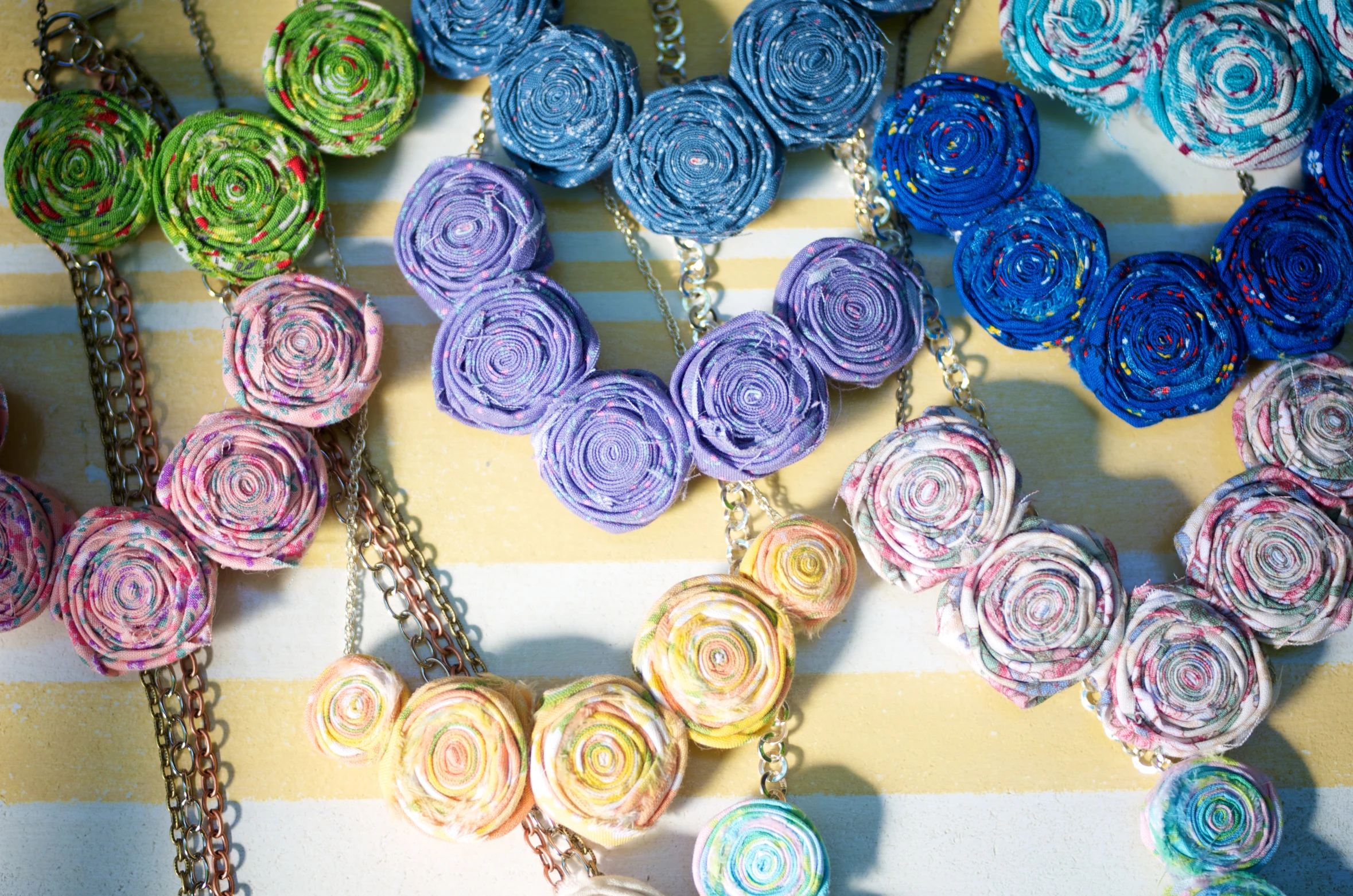 necklaces made of colored fabric on striped background