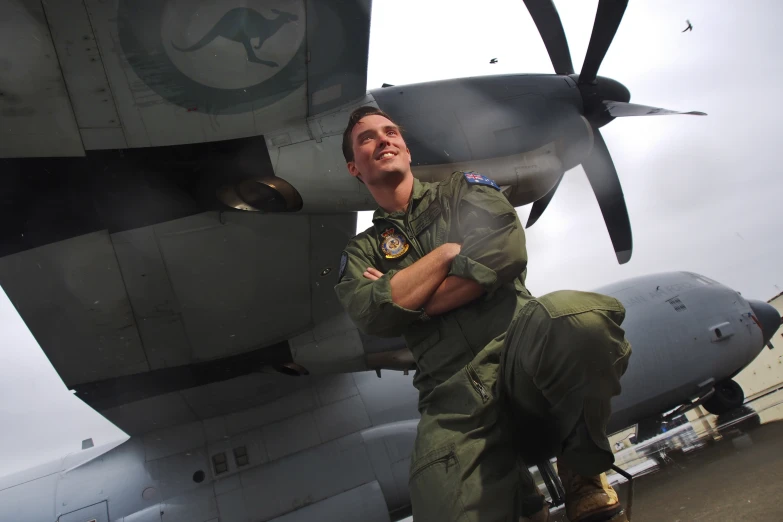 a man standing next to an airplane with his arms crossed