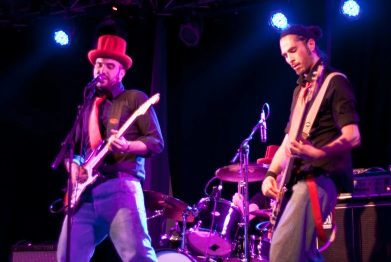 two men standing at microphones with guitars