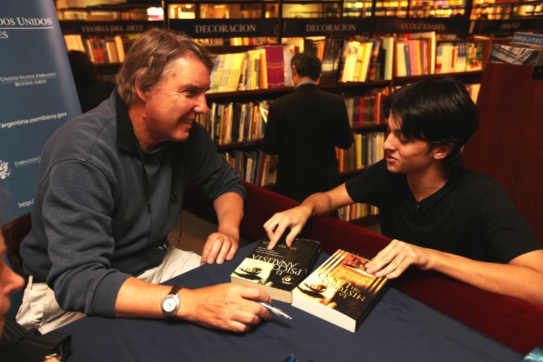 two people sitting at a table in a liry