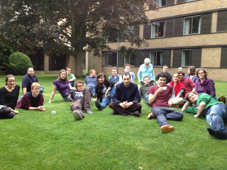 people sitting in a field with one person holding a phone