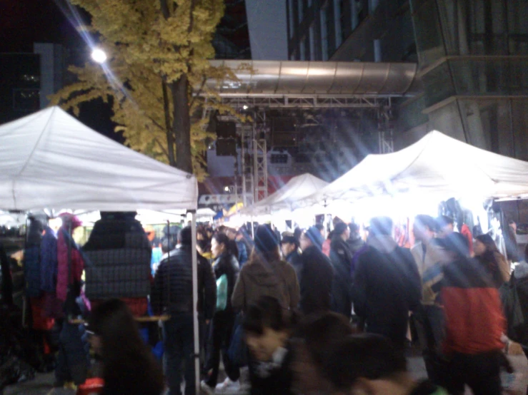 many people under a tent at a market place