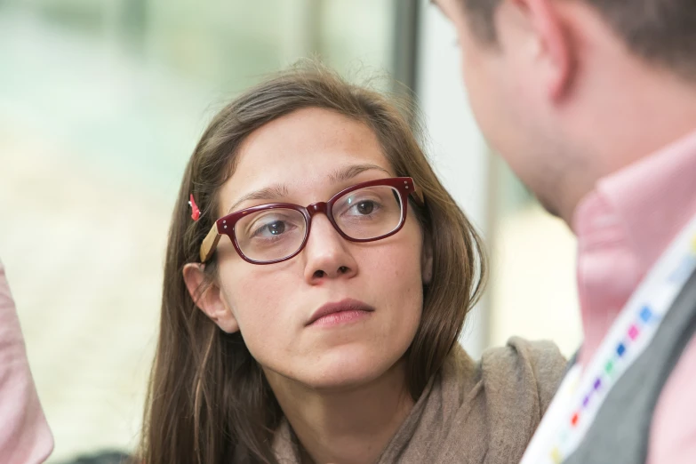 woman in glasses with a concerned look in front of a man