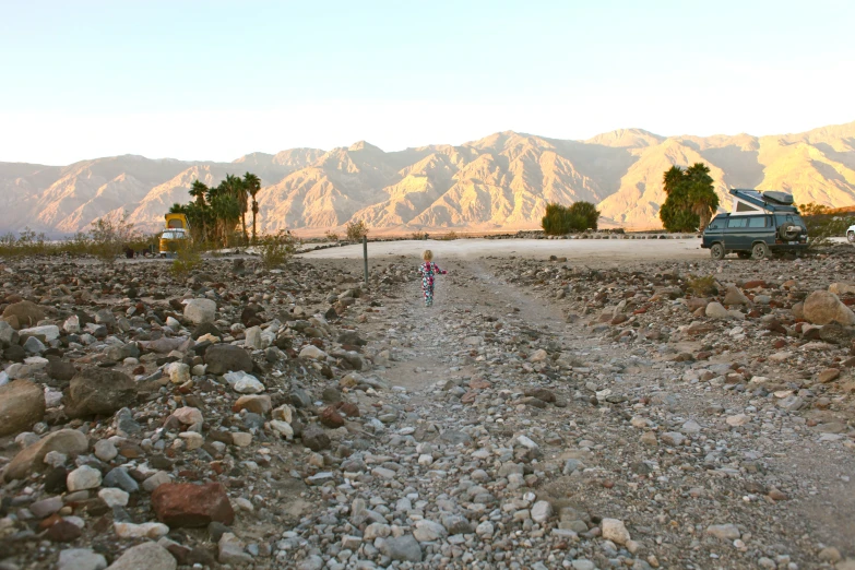 a dirt road surrounded by rocks with a car on the side