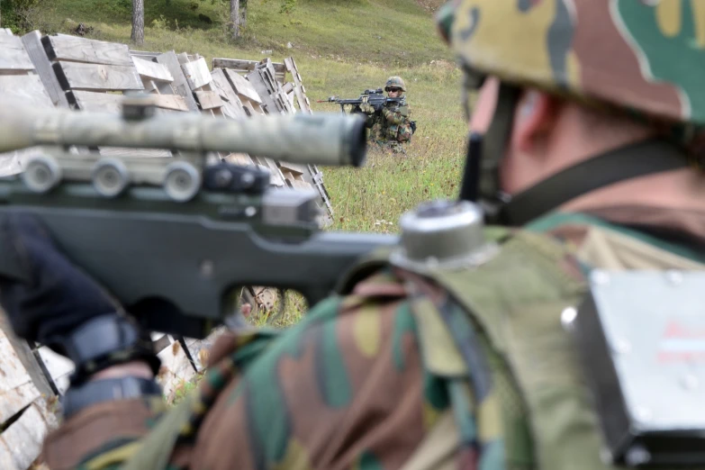 man is aiming at soing while wearing camouflage and holding a rifle