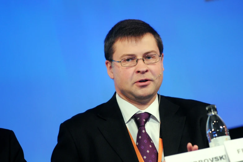 a man talking on a podium in a business suit