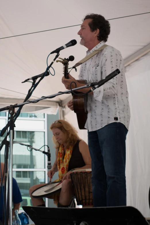 an older man playing on his instrument while another woman watches