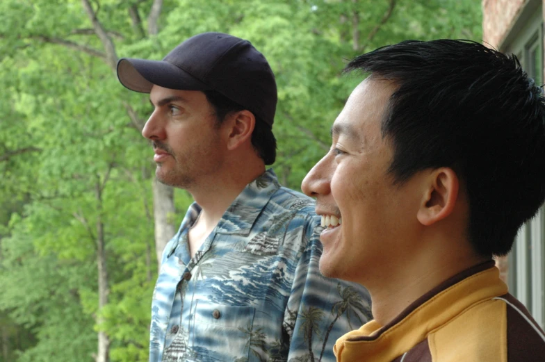 two men laughing together as they stand near trees