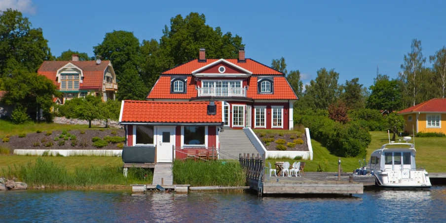 a red brick home on the water, with some boats nearby