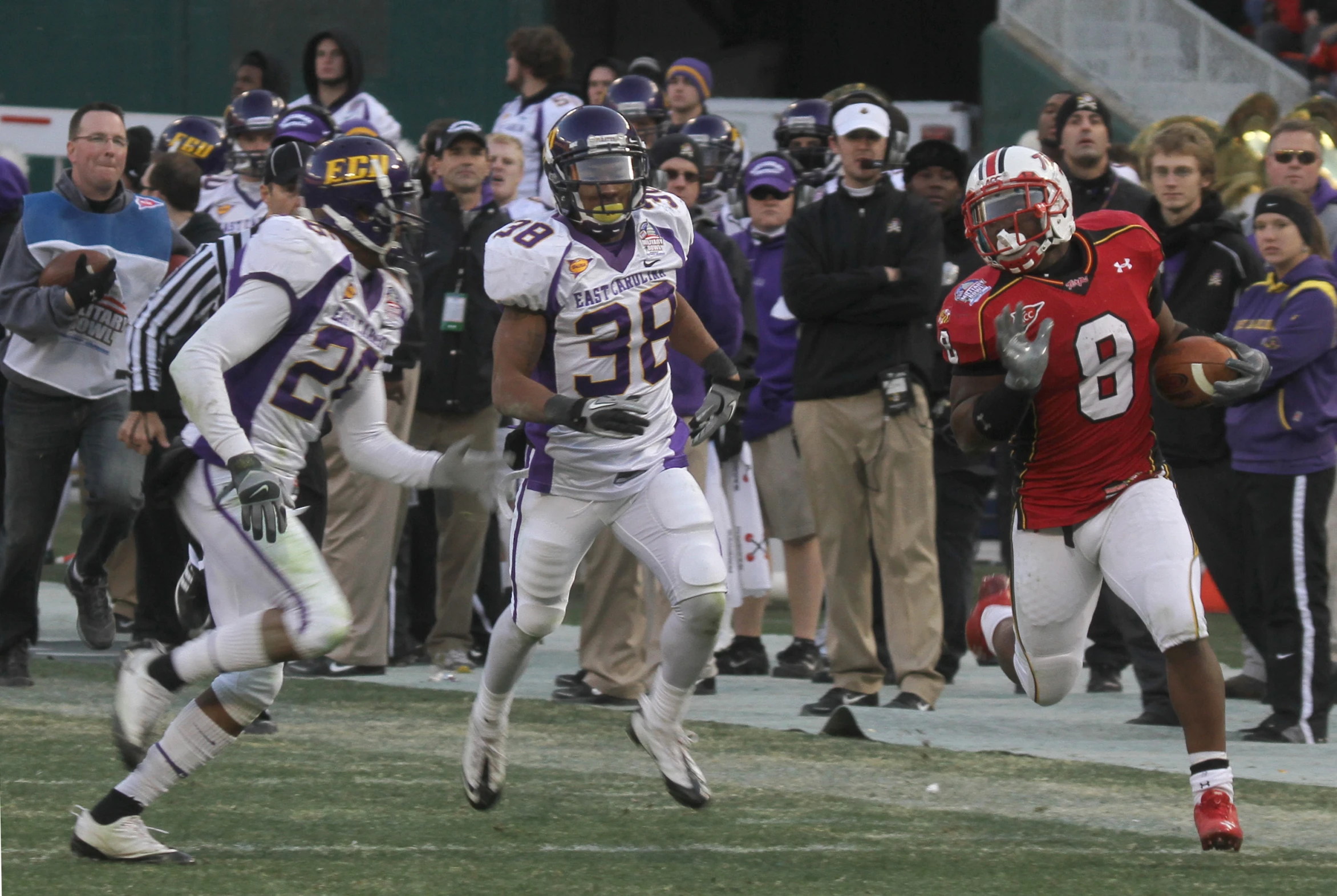 a football player runs with the ball in front of other players