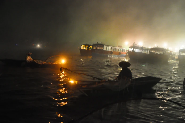 several people row boats in the night fog