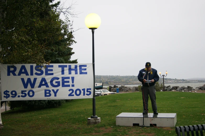 a man standing in the grass next to a sign