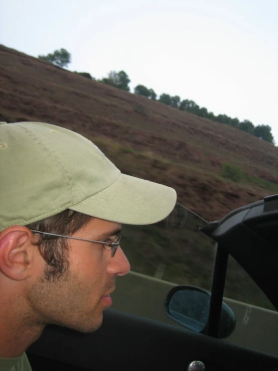 a man in glasses and a hat driving a car