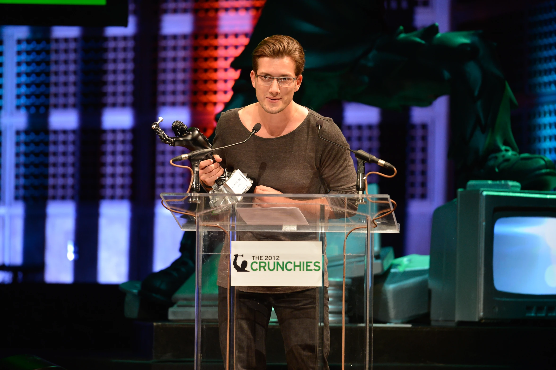 man holding an award in front of a television