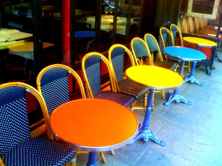 a row of yellow and blue dining tables outside a restaurant