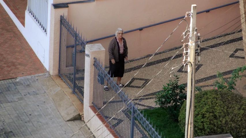 an older man is walking past a fence on the sidewalk