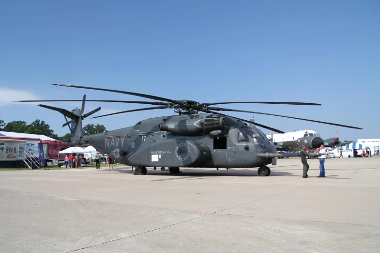 a large black helicopter sitting on top of an airport runway