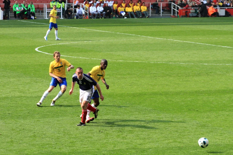 three soccer players running after the ball during a game