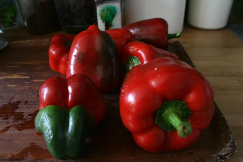 red peppers with green peppers sitting on a wooden tray