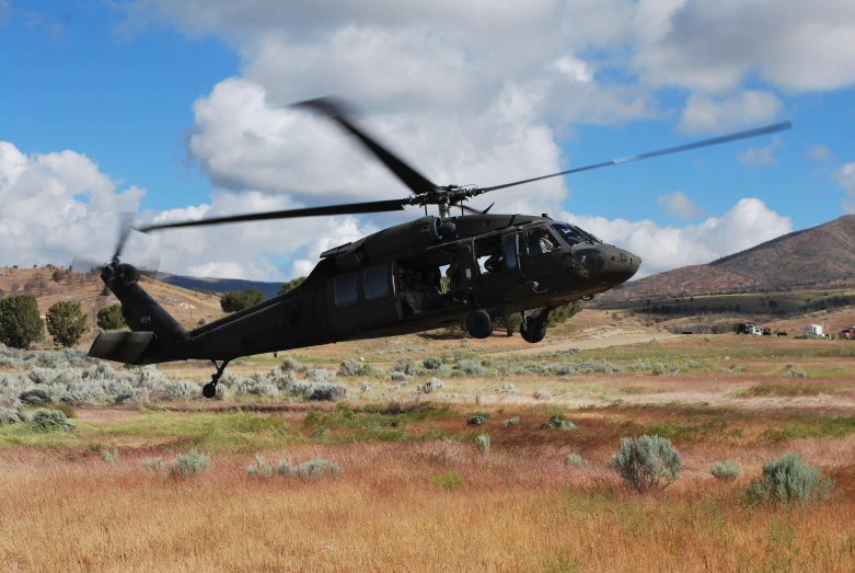 a helicopter is flying low over a desert plain