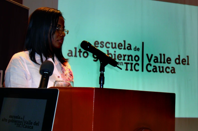 a woman standing behind a podium in front of a sign