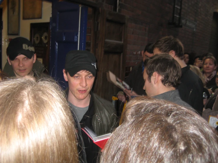 the young man is in a crowded area speaking to other people