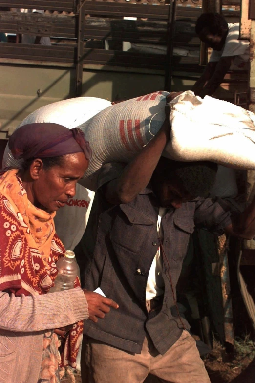 two men carrying bags with one carrying a bottle