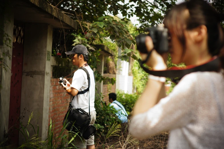 woman taking a po of man standing next to house