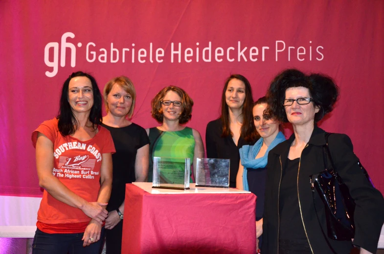 a group of women posing behind a cake