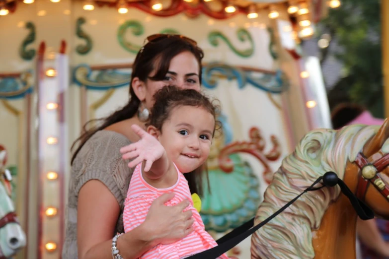 a woman and a little girl ride a carousel