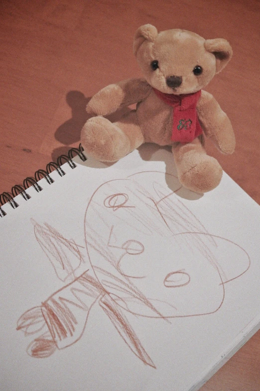 a teddy bear that is on top of a notepad