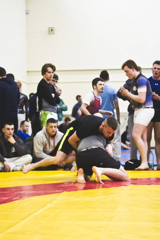 wrestlers on a wrestling mat with referee watching