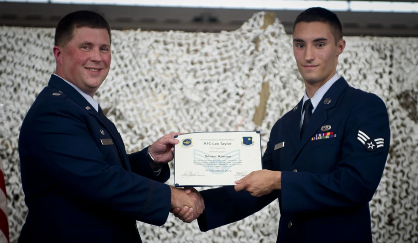 two men in uniforms holding up an award