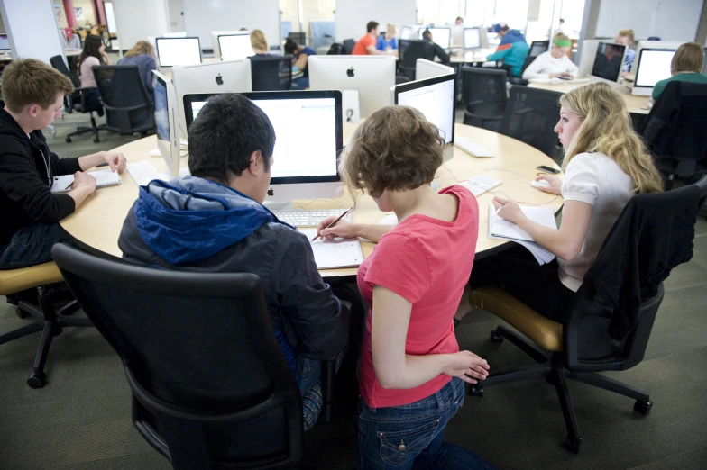 a woman and children working at multiple computers