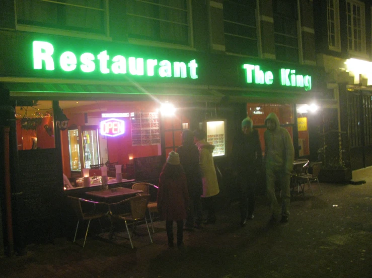 people standing outside the entrance to a restaurant at night