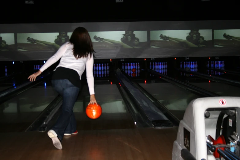a woman with a bowling ball in her hands is bowling down the lane