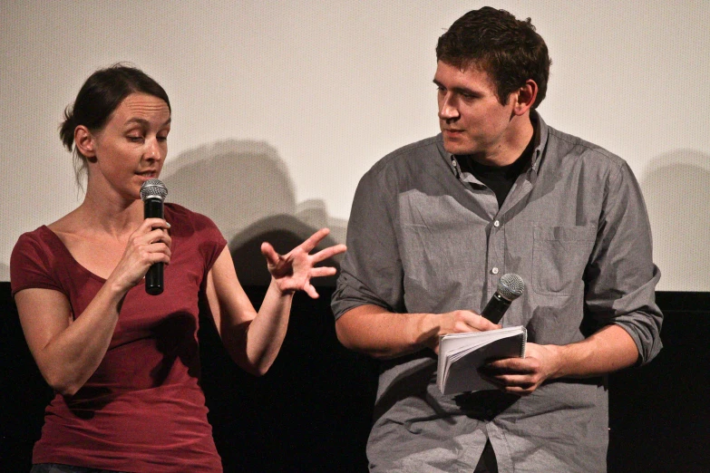 a man and woman with microphones talking on stage