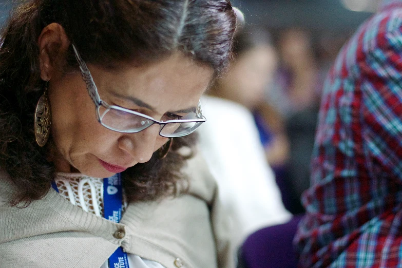 an older woman using her cell phone while a crowd of people wait in line behind