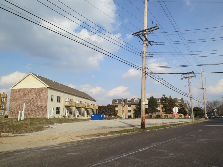 an empty road lined with buildings with telephone poles and houses behind it