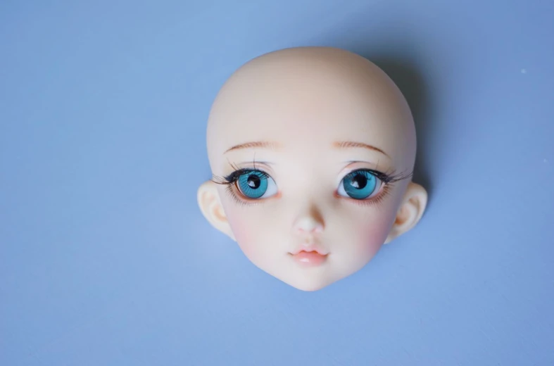 a doll head with big blue eyes on a blue background