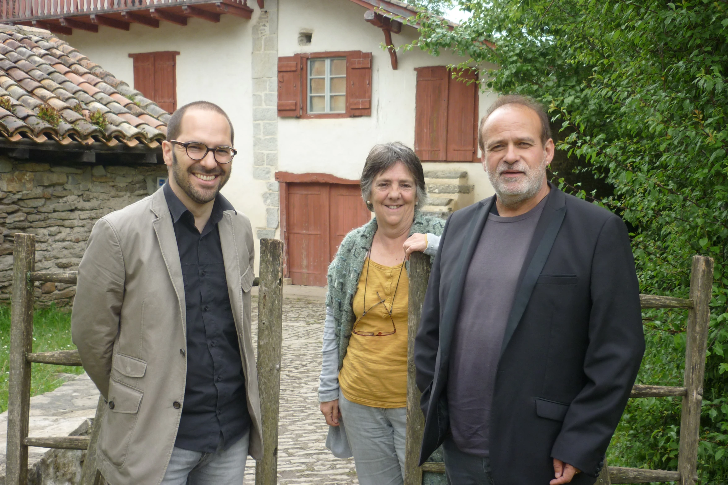 three people stand on the sidewalk next to an older house