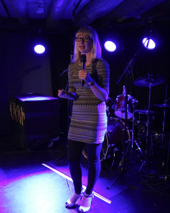 a female standing on the stage speaking into a microphone