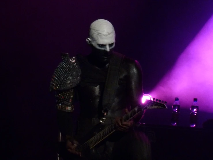 a man wearing a body suit and headpiece holding a guitar