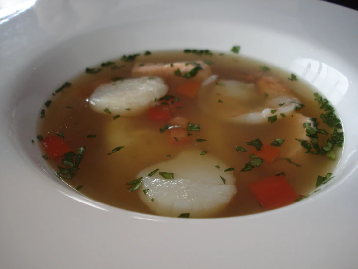 a soup dish served on a plate, with potatoes and carrots